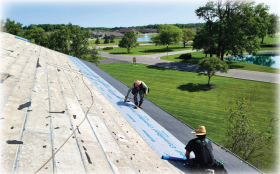 Crew laying underlayment on roof